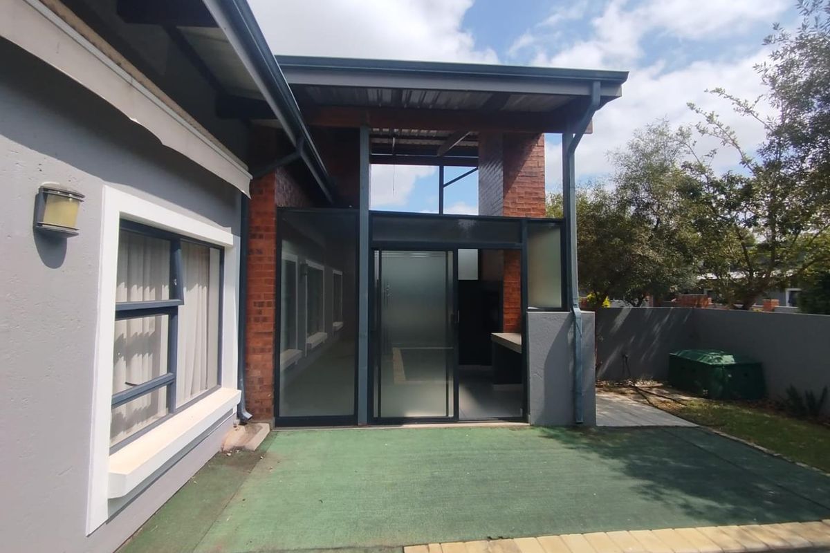 Rear exterior view of the apartment featuring a covered patio area, sliding glass doors, and a swimming pool with paved surround.