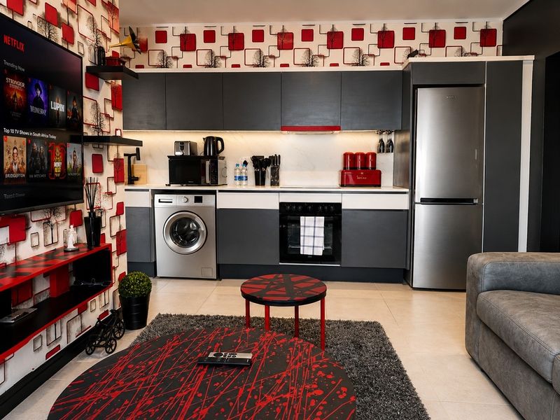 Modern open-plan kitchen featuring sleek dark cabinetry, integrated appliances, and contemporary tiled flooring, seamlessly connected to the living area.