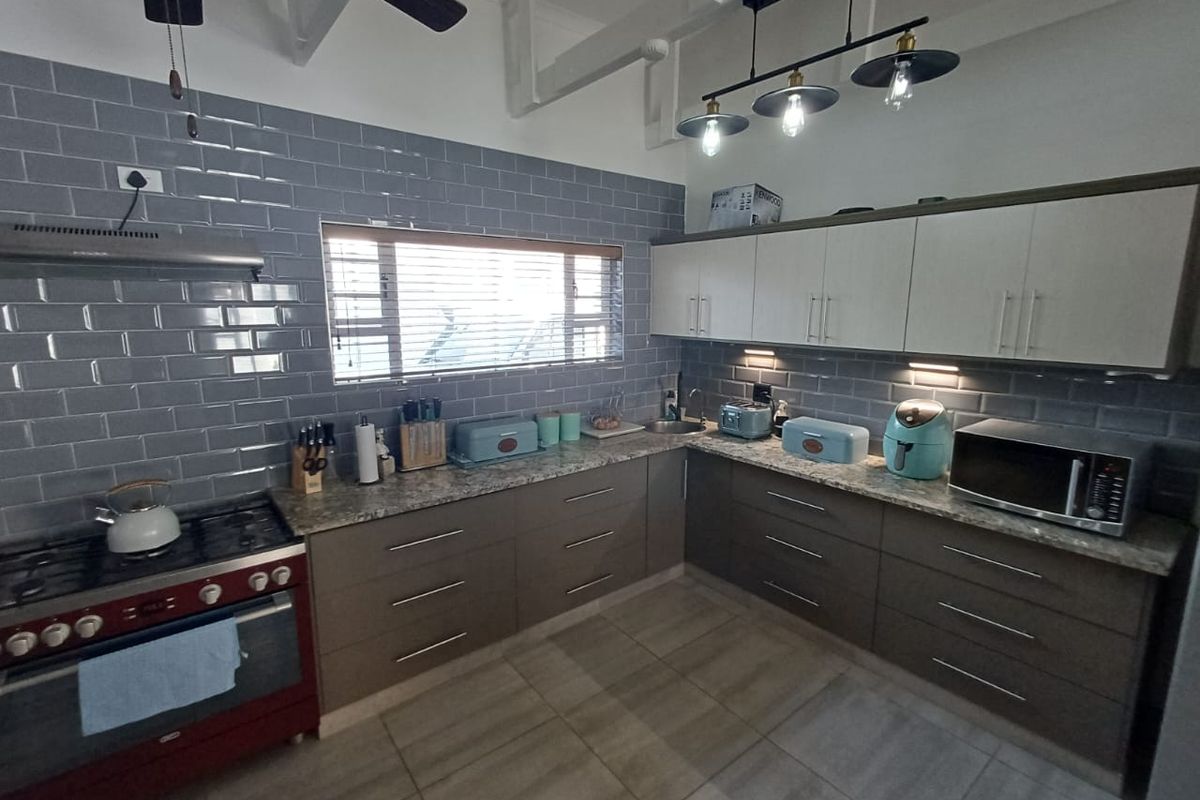 Modern kitchen featuring grey subway tile backsplash, stone countertops, ample cabinetry, and a gas stove with an extractor fan.