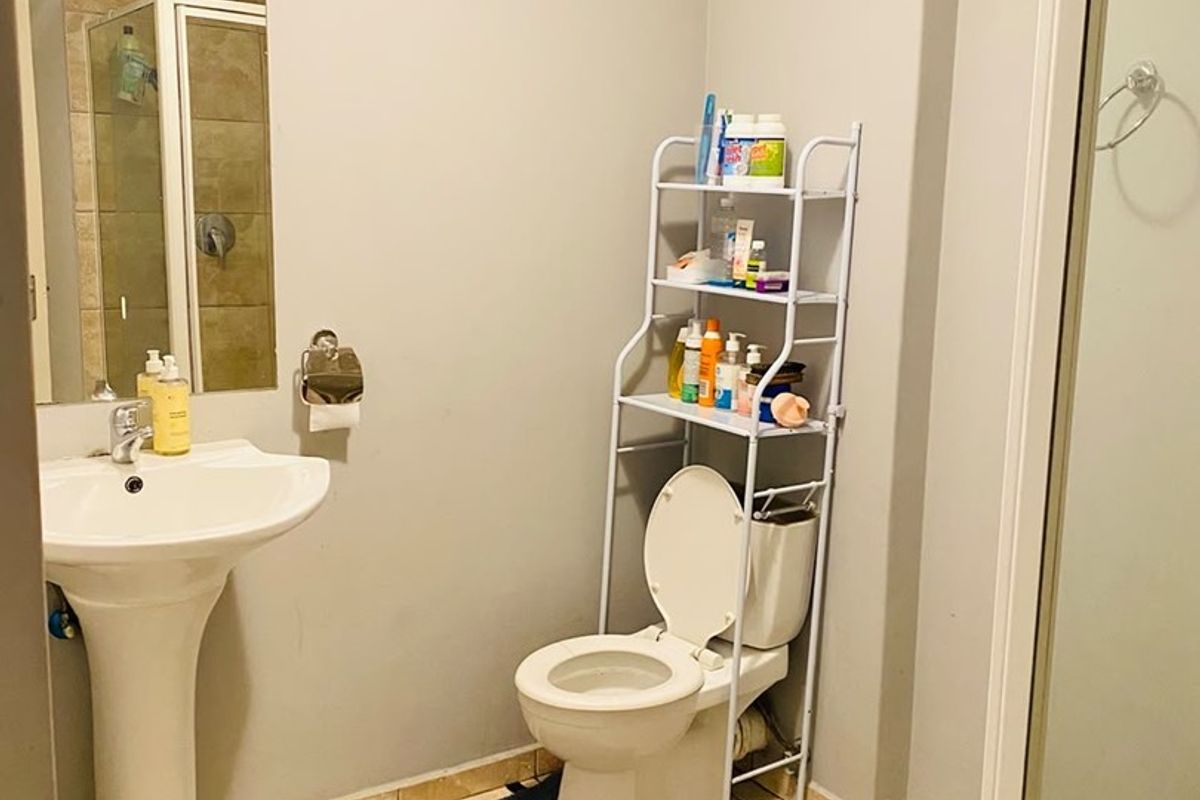 A functional bathroom featuring a pedestal basin, toilet, and a separate shower enclosure with tiled flooring and neutral wall finishes.