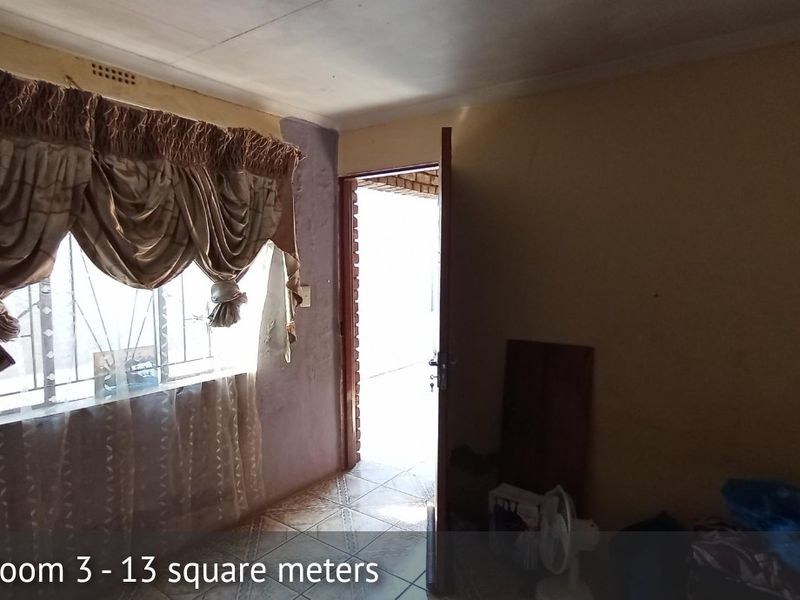 A bedroom featuring tiled flooring and security bars on the window, requiring cosmetic updates to the wall finishes.