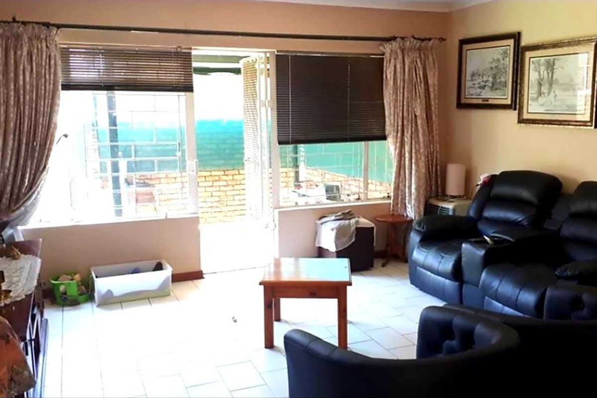 A living room featuring tiled flooring and a sliding glass door providing access to an outdoor patio area.