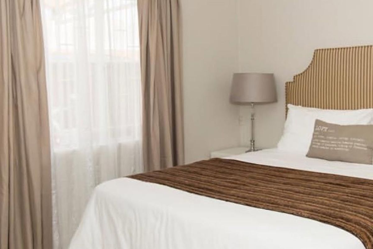 A well-maintained bedroom featuring neutral wall tones, tiled flooring, and classic cove cornicing, providing a clean and comfortable living space.