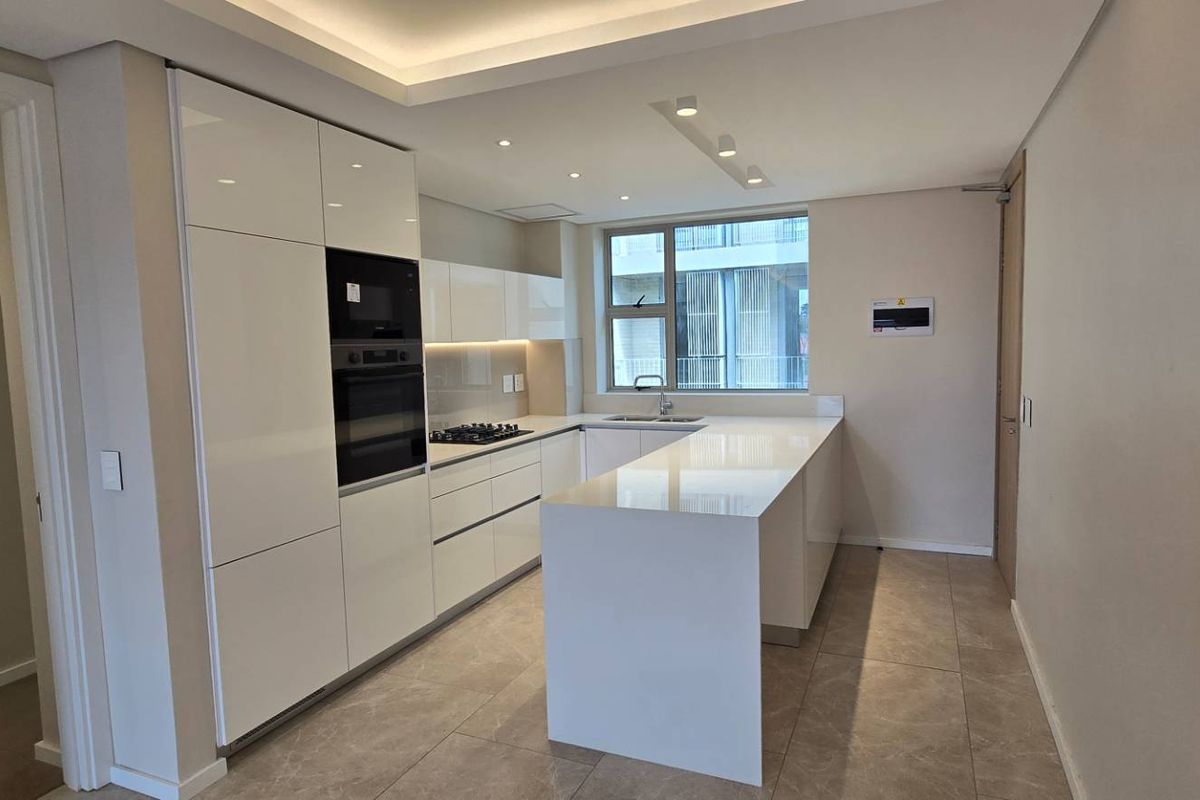 Modern kitchen featuring sleek white cabinetry, stone countertops, integrated appliances, and recessed lighting, offering a clean and functional culinary space.