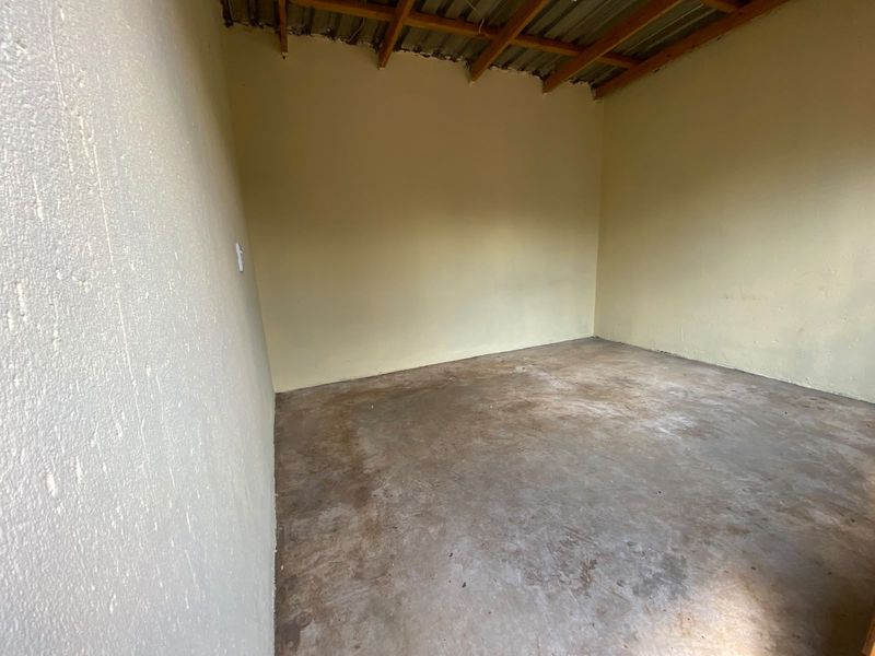 A basic, unfinished utility space featuring exposed timber rafters and a concrete floor, suitable for storage or workshop conversion.