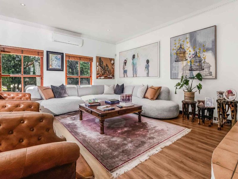 A spacious and well-lit living room featuring timber-framed windows, a tiled hearth, and a wall-mounted split-system air conditioner.