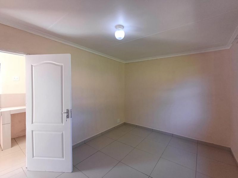 A clean, empty bedroom featuring neutral tiled flooring and a coved ceiling, offering a blank canvas for personalization.