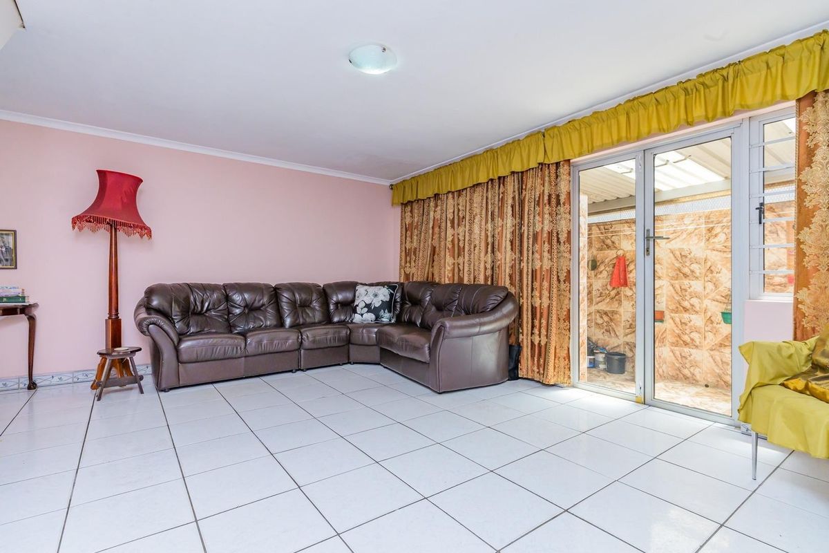 A living room featuring white tiled flooring and a sliding glass door providing access to an outdoor area.
