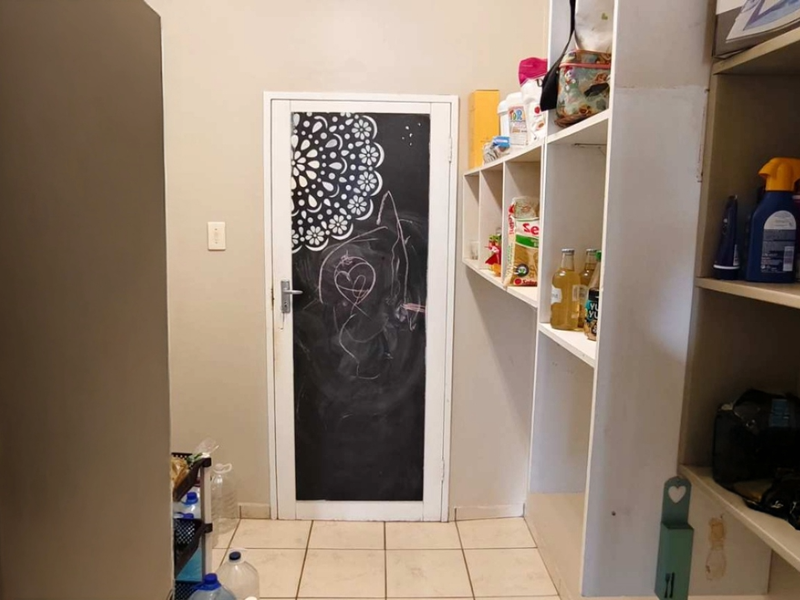 A functional scullery or pantry area featuring built-in open shelving and tiled flooring, providing convenient additional storage space.