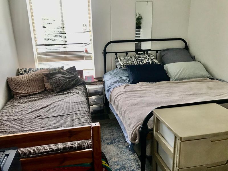 A functional bedroom featuring a window with venetian blinds, providing natural light and a neutral backdrop for potential interior updates.
