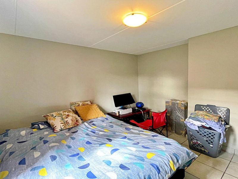 A functional bedroom featuring tiled flooring and neutral wall finishes, providing a blank canvas for personalization.