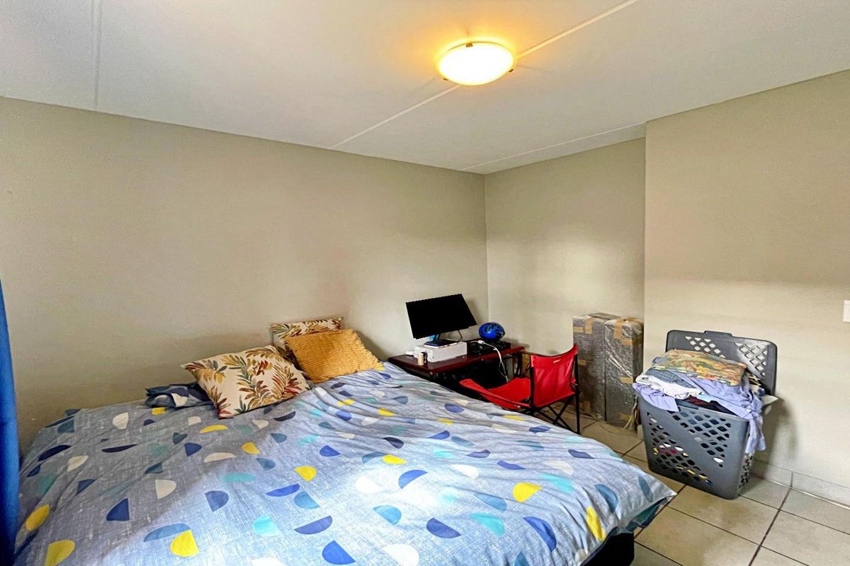 A functional bedroom featuring tiled flooring and neutral wall finishes, providing a blank canvas for personalization.