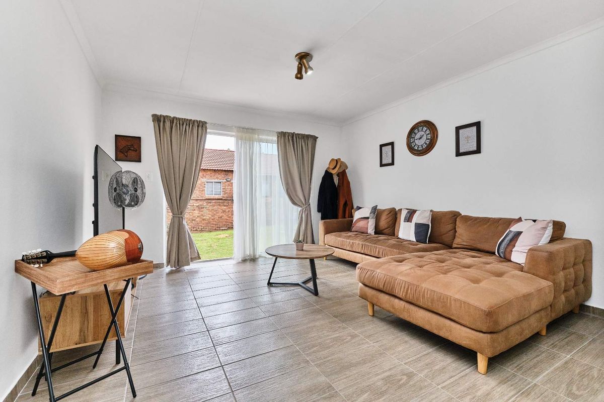 A bright living room featuring tiled flooring and sliding glass doors that provide direct access to the rear garden area.