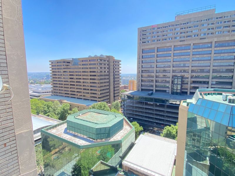 An elevated urban view overlooking surrounding commercial buildings and city infrastructure from an apartment balcony.