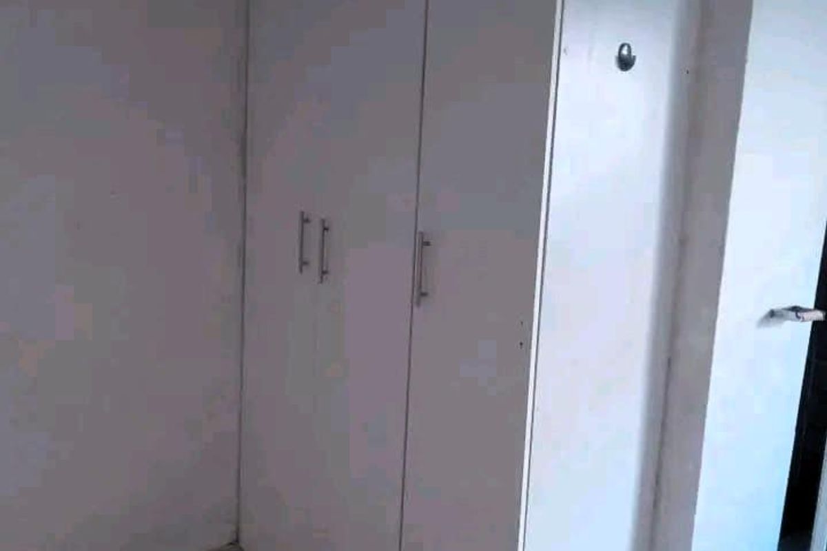 A bedroom interior featuring built-in white cabinetry and tiled flooring.