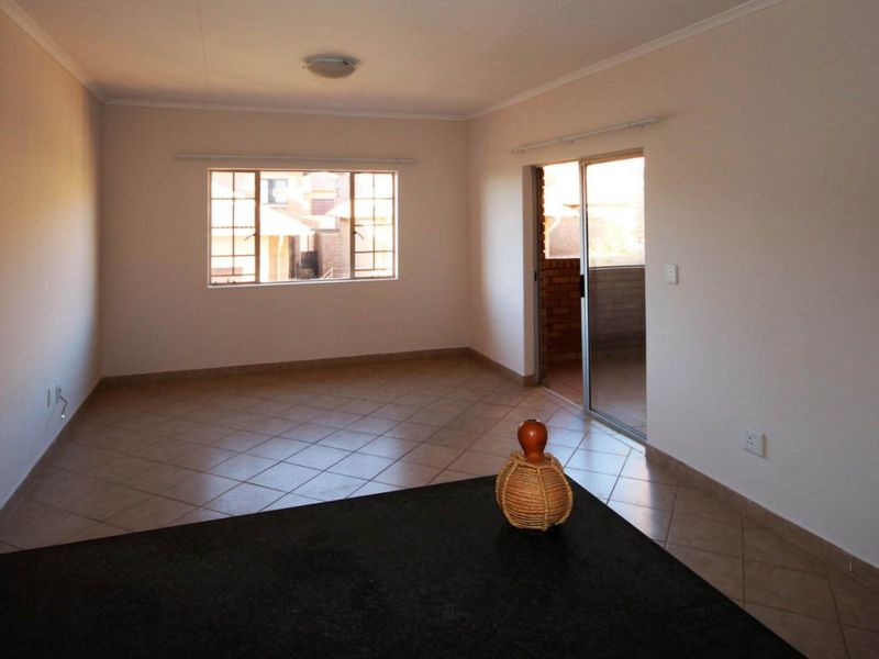 Spacious open-plan living area featuring tiled flooring, a granite countertop, and direct access to an outdoor balcony through a sliding glass door.
