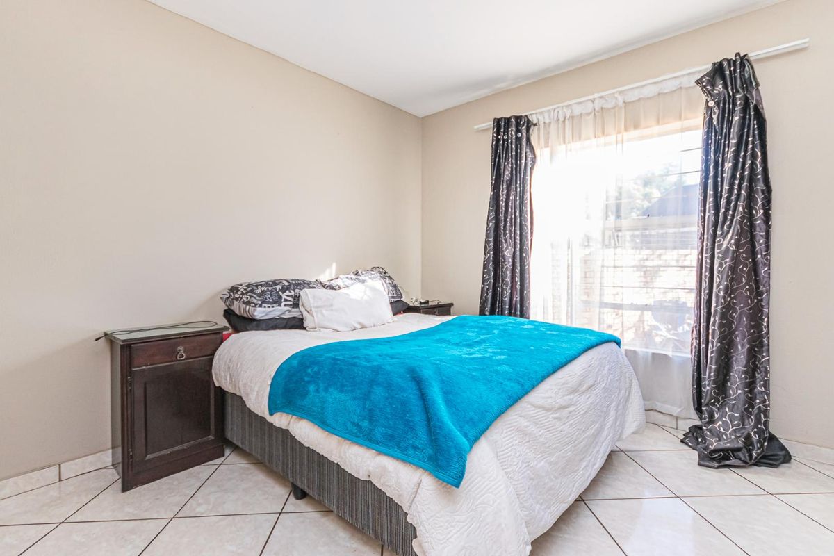 A bedroom featuring tiled flooring and a large window with curtain tracks, providing natural light.