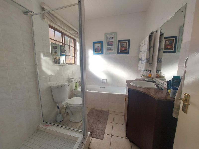 A functional bathroom featuring a separate shower enclosure, a built-in bathtub, a vanity cabinet with a basin, and tiled finishes throughout.