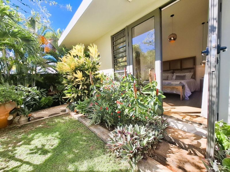 A well-maintained rear garden area featuring lush landscaping and direct access to the interior through large sliding glass doors.