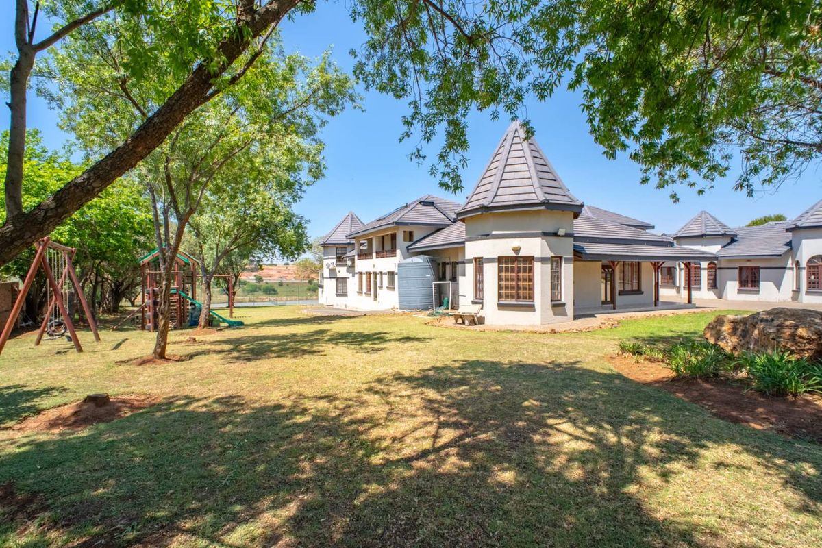 Spacious rear garden featuring a well-maintained lawn, mature trees, and a view of the property's rear elevation with distinctive turret-style roof architecture.