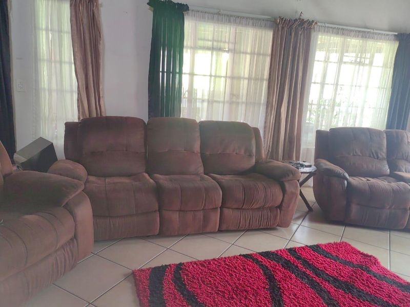 A living room area featuring tiled flooring and large windows that allow for natural light.