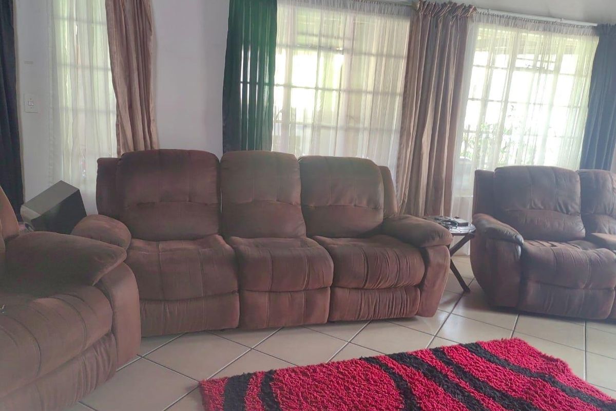 A living room area featuring tiled flooring and large windows that allow for natural light.