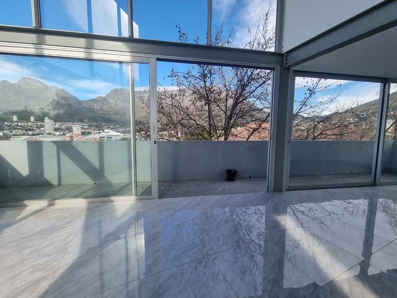 Spacious open-plan living area featuring floor-to-ceiling glass sliding doors, polished marble-look tiles, and expansive mountain views from the attached balcony.