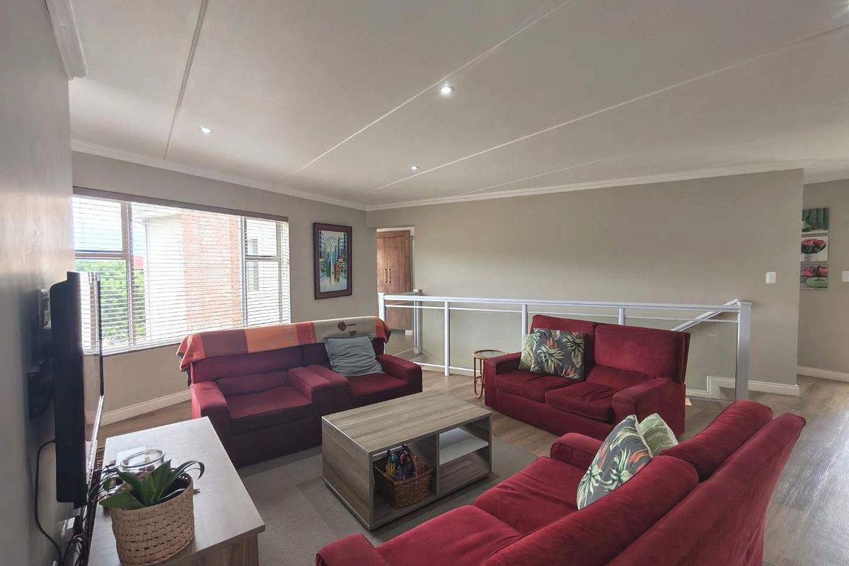 Spacious living area featuring neutral wall tones, recessed ceiling lighting, and a white balustrade overlooking the lower level.
