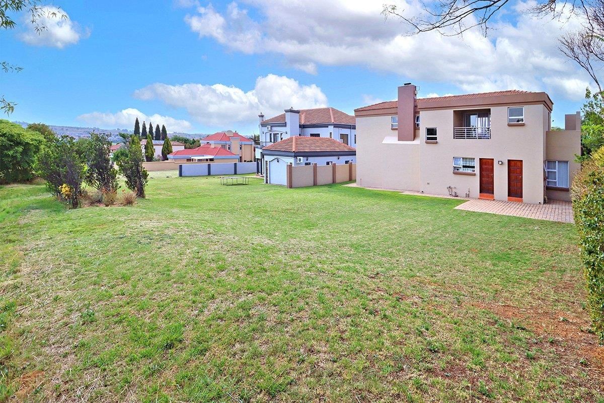 Spacious rear garden area featuring a paved patio, established lawn, and views of the surrounding residential estate.