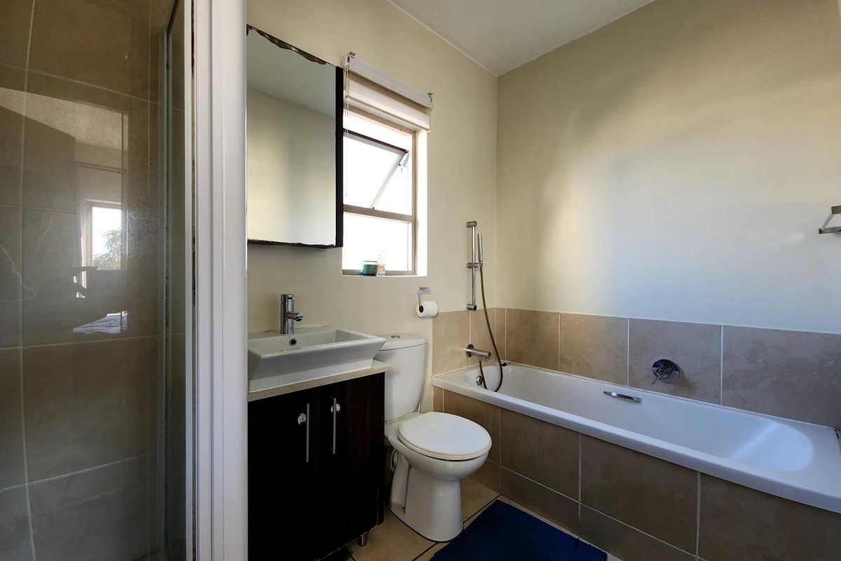 A functional bathroom featuring a separate shower enclosure, a built-in bathtub with tiled surround, and a vanity basin with storage.
