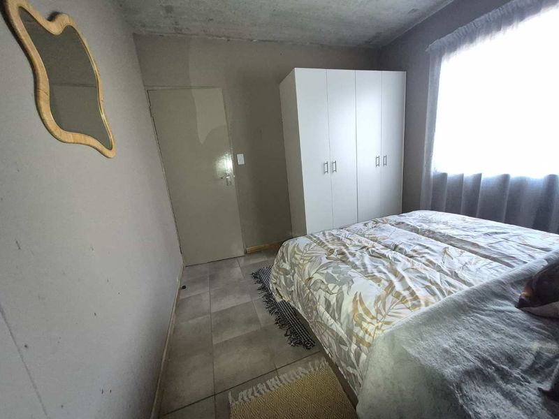 A bedroom featuring tiled flooring and a built-in wardrobe, requiring cosmetic updates to the walls and ceiling to improve its overall condition.