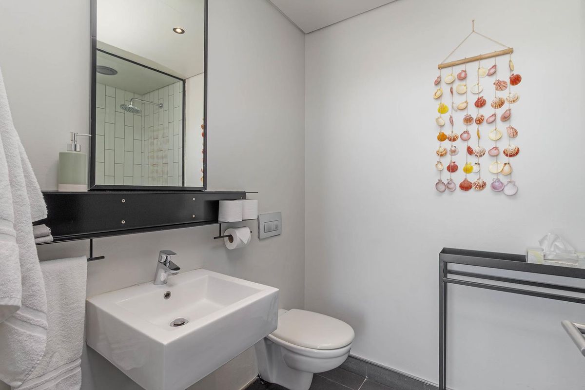 Modern bathroom featuring a wall-mounted vanity basin, concealed cistern toilet, and a glass-enclosed shower with subway tile surround.