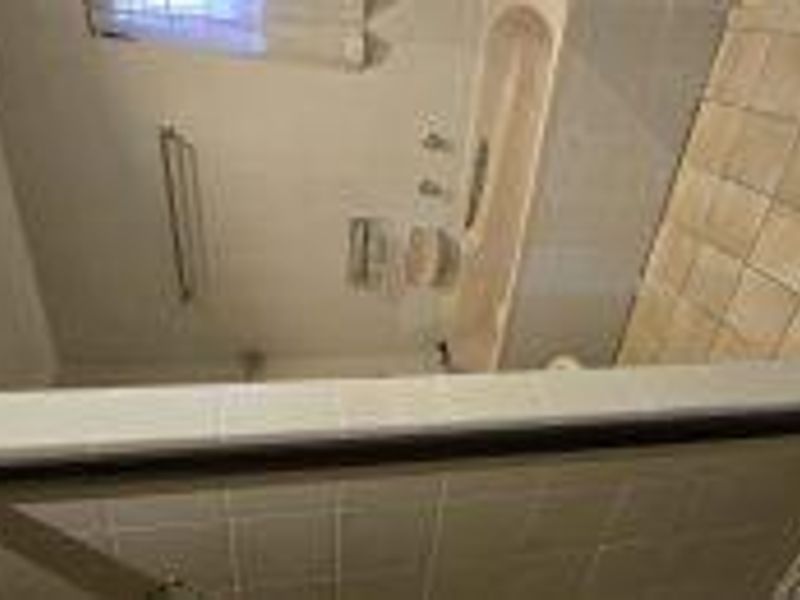 A dated bathroom featuring a bathtub, separate shower enclosure, and tiled finishes, offering potential for a modern renovation.