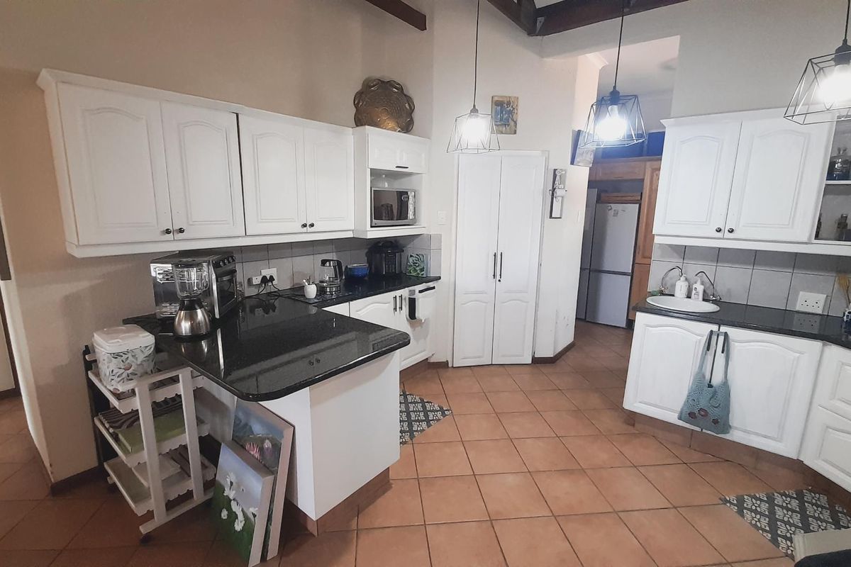 A functional kitchen featuring white cabinetry, dark granite countertops, tiled flooring, and pendant lighting, offering a classic layout with ample storage space.