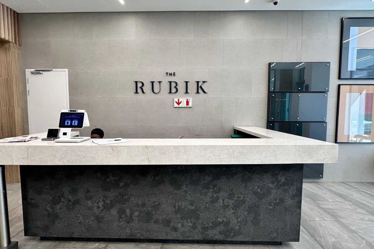 Modern office building reception area featuring a stone-clad feature wall, professional reception desk, and high-quality tiled flooring.