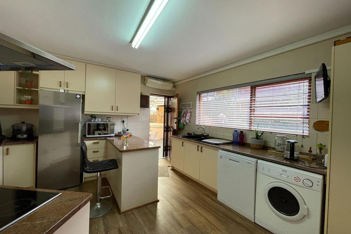 Functional kitchen featuring laminate cabinetry, granite-look countertops, integrated sink, and space for under-counter appliances, with direct access to the outdoor area.