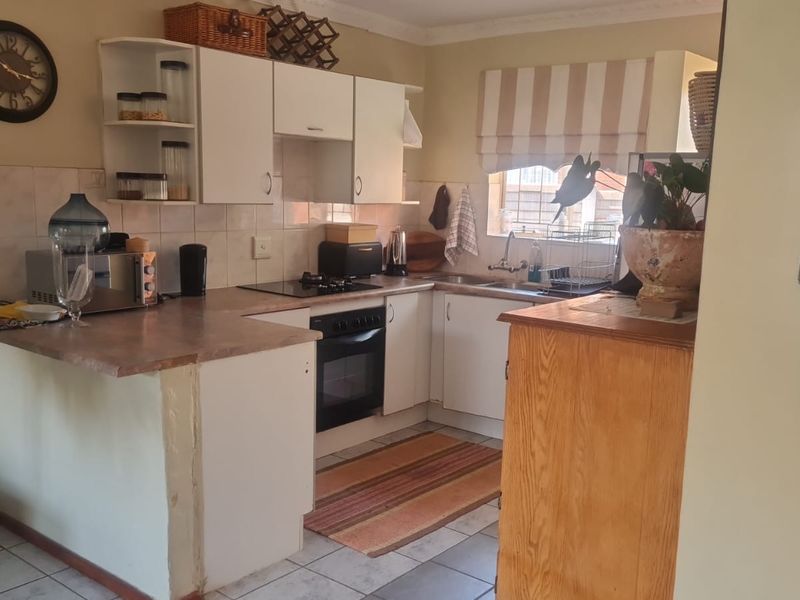Functional kitchen featuring built-in cabinetry, laminate countertops, integrated oven and hob, and tiled flooring, offering a practical layout for daily meal preparation.