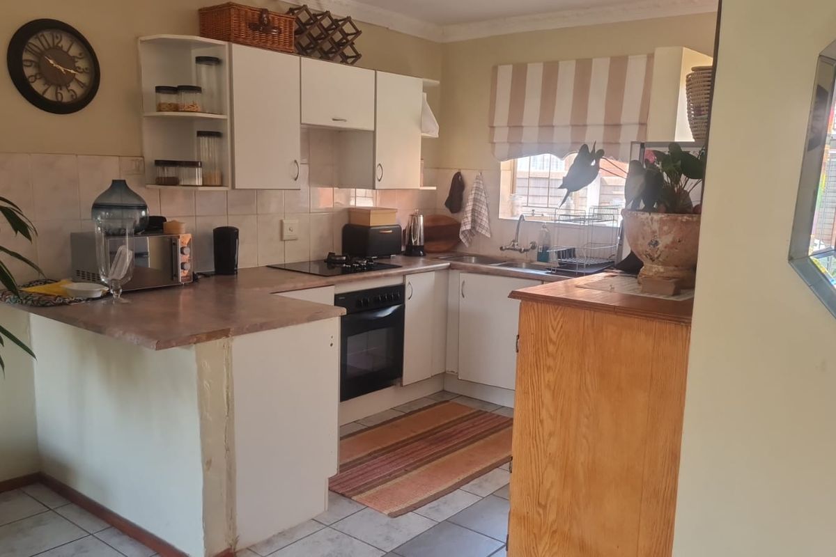 Functional kitchen featuring built-in cabinetry, laminate countertops, integrated oven and hob, and tiled flooring, offering a practical layout for daily meal preparation.
