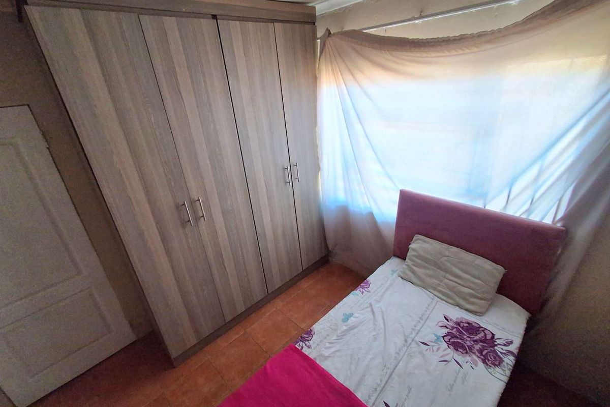 A bedroom featuring tiled flooring and a built-in wardrobe with wood-grain finish.