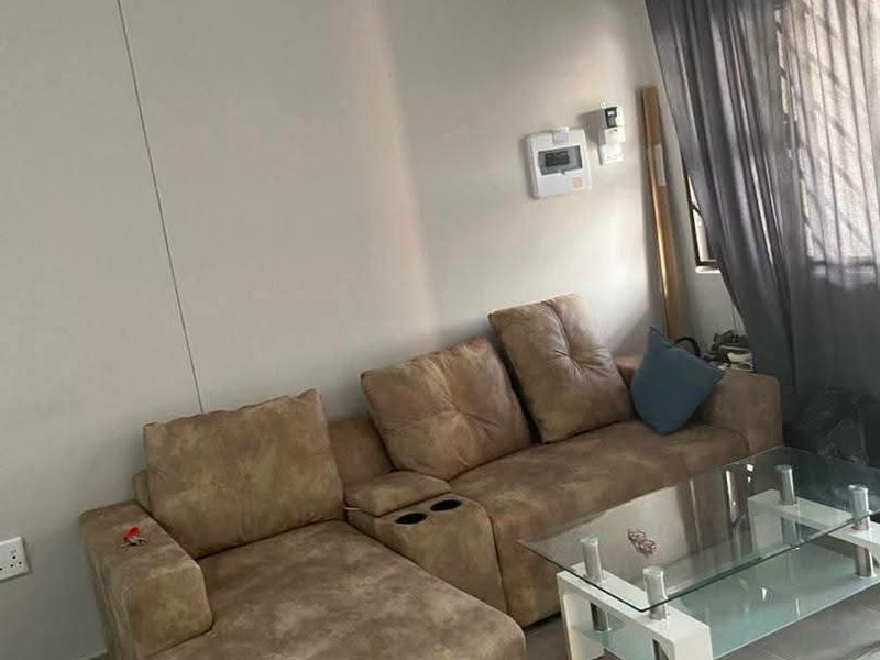 A living room featuring neutral tiled flooring and a security alarm system, providing a functional and well-lit space.