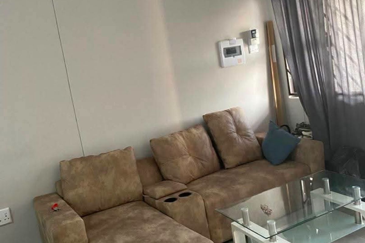A living room featuring neutral tiled flooring and a security alarm system, providing a functional and well-lit space.