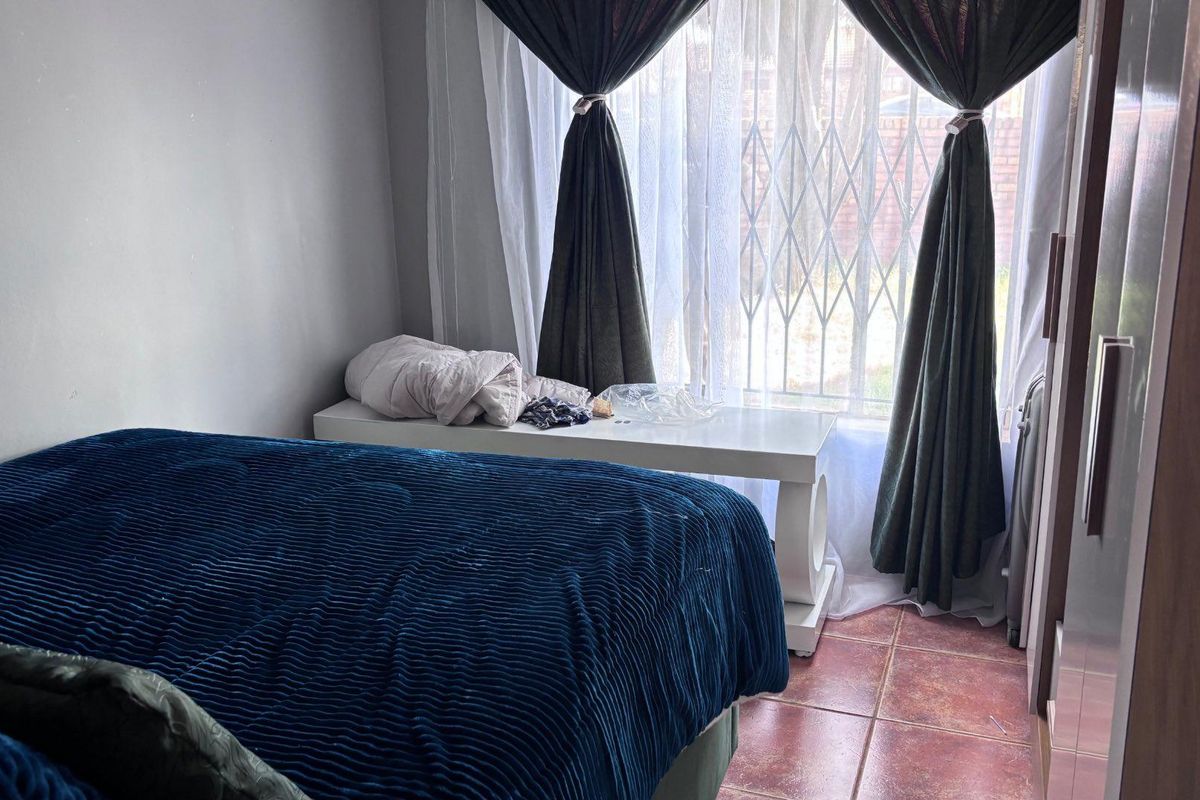 A bedroom featuring tiled flooring, built-in wardrobe, and security gate on the window.