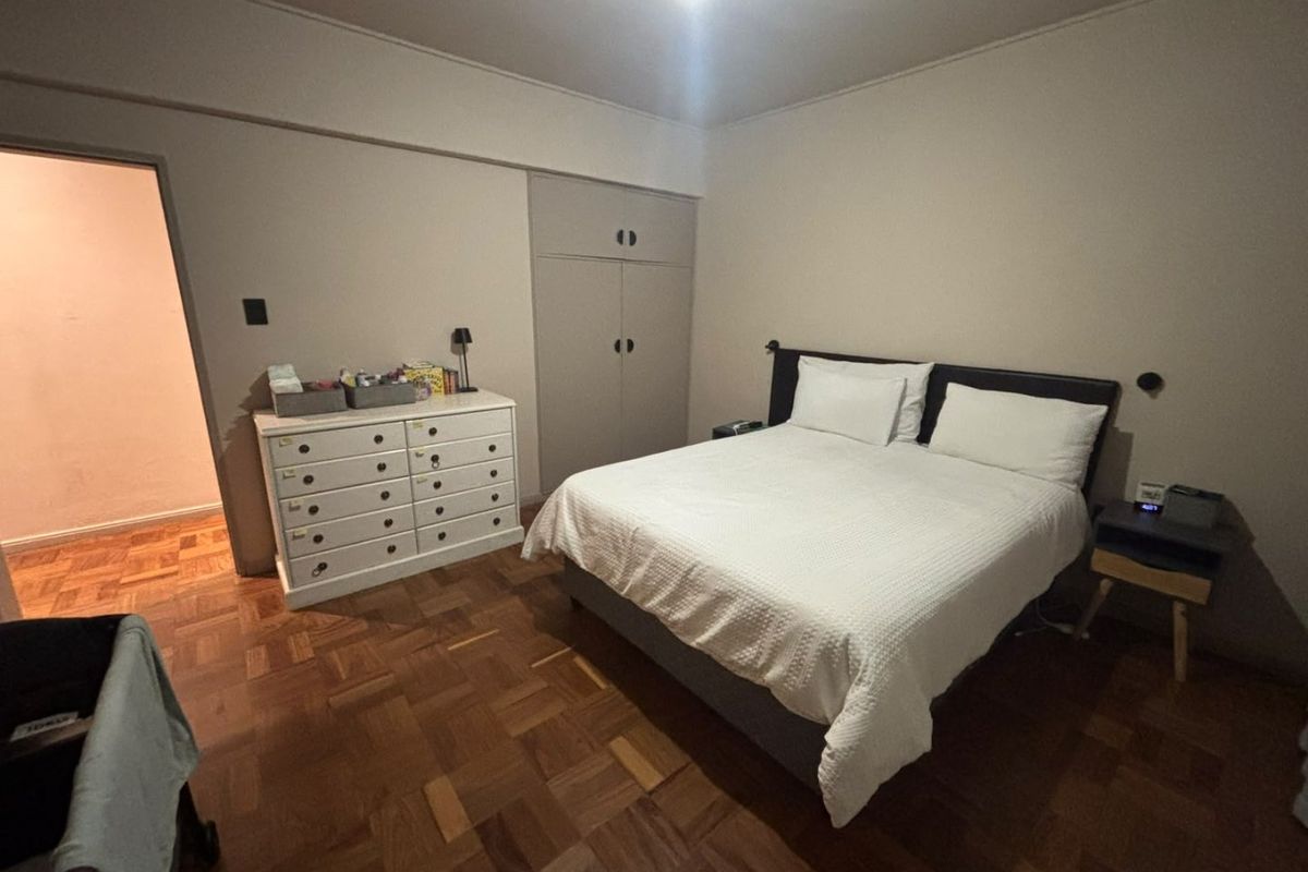 A bedroom featuring classic parquet flooring and a built-in wardrobe, offering a functional layout with neutral wall finishes.