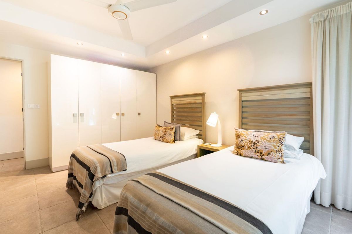 A well-maintained bedroom featuring built-in high-gloss white cabinetry, recessed ceiling lighting, a ceiling fan, and neutral floor tiling.