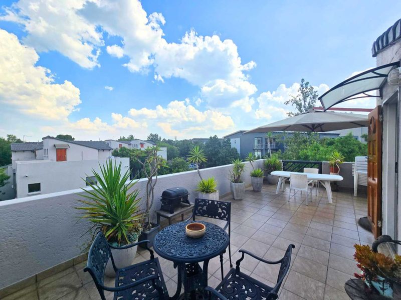 Spacious outdoor balcony featuring tiled flooring, a protective awning, and a parapet wall, offering an open-air space for relaxation.