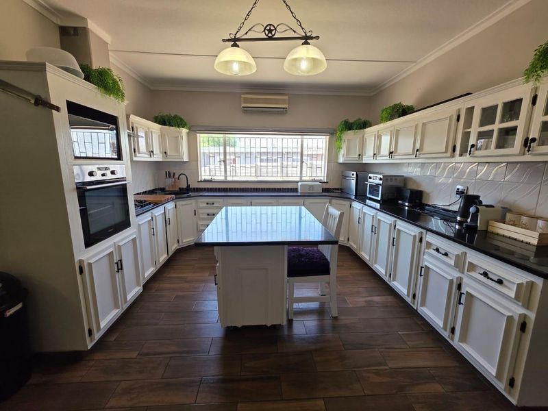 Spacious kitchen featuring white cabinetry, granite countertops, a central island, built-in oven and microwave, and tiled flooring.