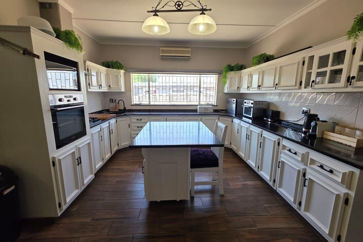 Spacious kitchen featuring white cabinetry, granite countertops, a central island, built-in oven and microwave, and tiled flooring.