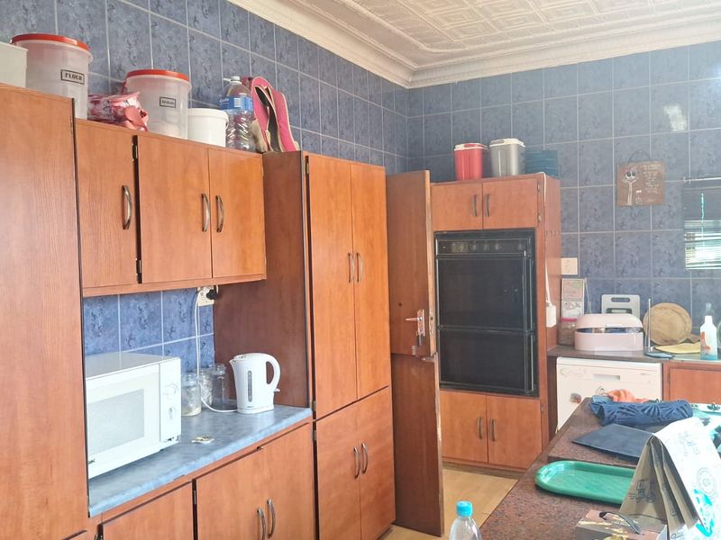 A functional kitchen featuring extensive wooden cabinetry, a double wall oven, and tiled wall finishes, offering a traditional layout with ample storage space.