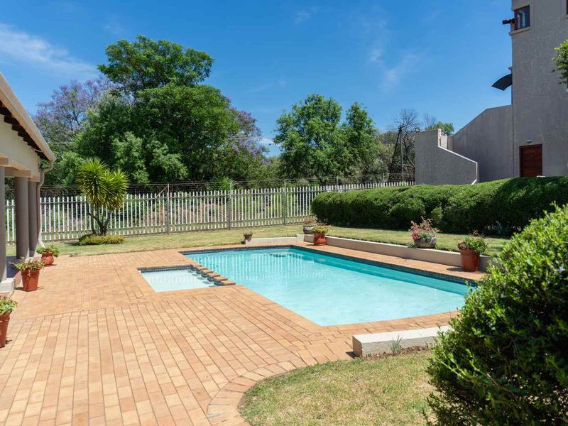 A well-maintained outdoor pool area featuring a paved patio, clear swimming pool, and landscaped garden surroundings, perfect for relaxation and outdoor entertainment.