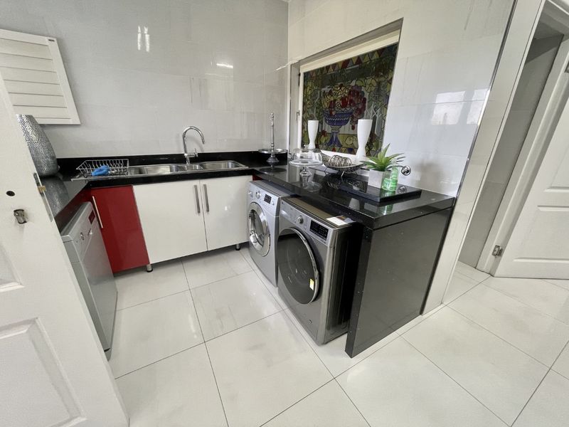A functional laundry area featuring granite countertops, built-in cabinetry, a stainless steel sink, and decorative stained glass window detail.